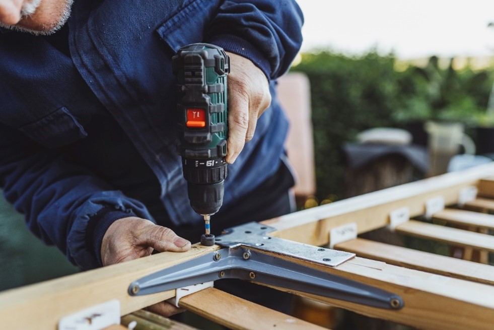 Workman drilling bracket into wood