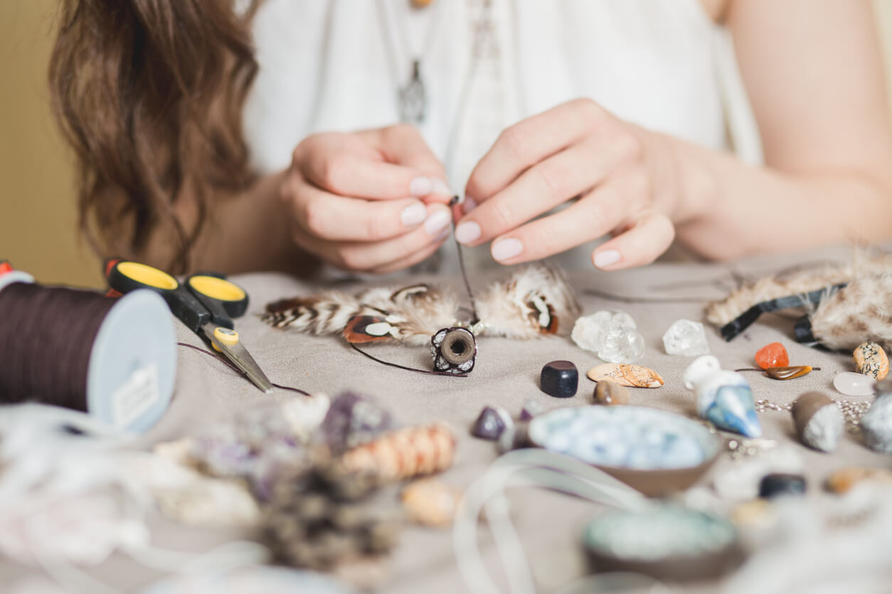 Woman hands making handmade gemstone jewelry, home workshop.