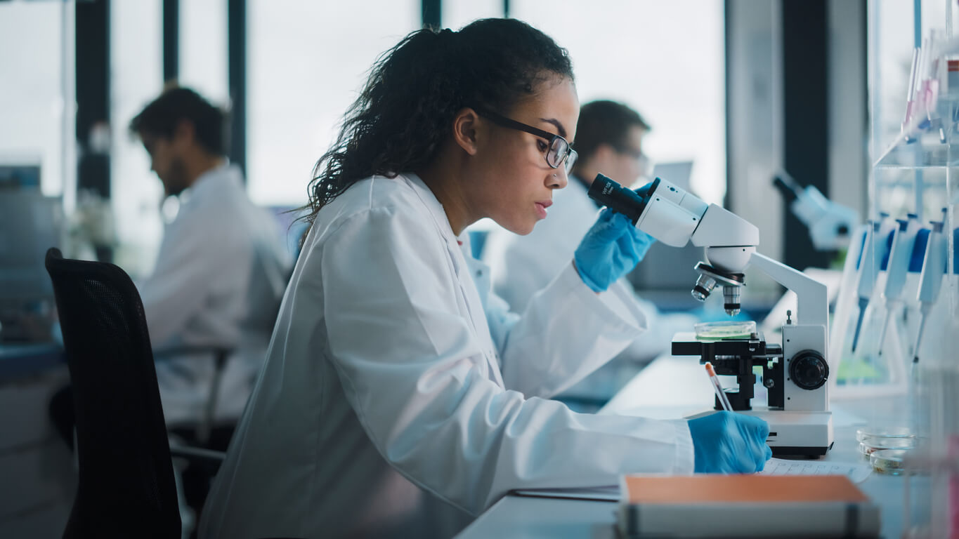 Medical Science Laboratory: Beautiful Black Scientist Looking Under Microscope Does Analysis of Test Sample.