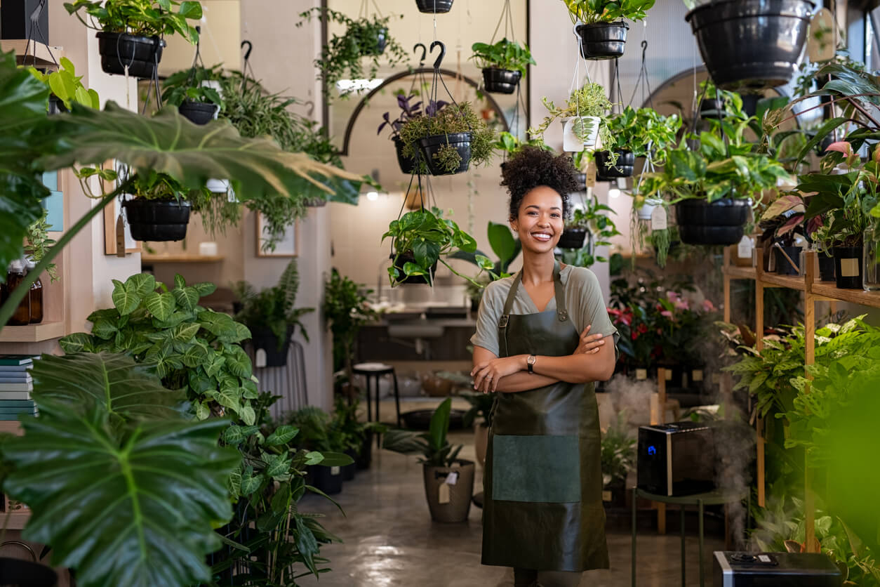 Woman stood in her shop full of plants.